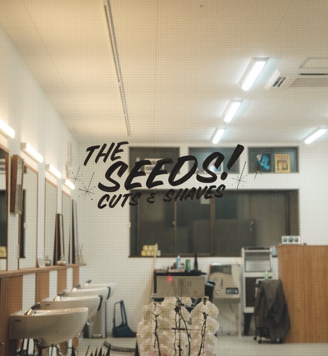 The seedsの入口越しに見える店内ロゴとバーバーショップ